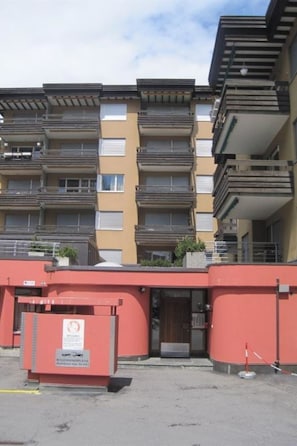 A multi-story residential building with balconies, a red entrance, and a sign indicating a no-smoking area. - Quellenhof A07 Appartement/Fewo, Dusche oder Bad, WC 1½-Zimmerwohnung by Interhome (Davos)