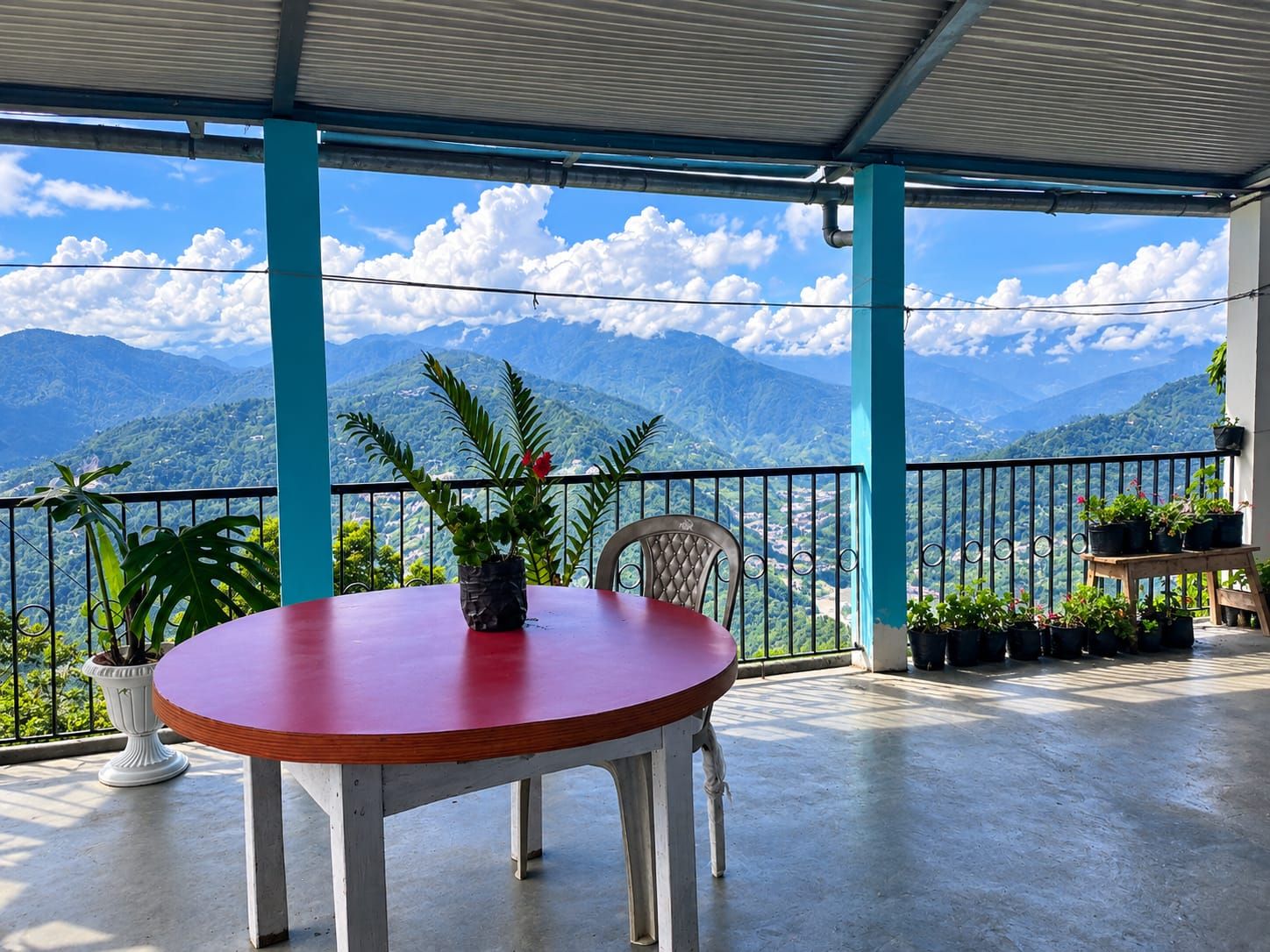 A covered outdoor seating area with a table and chairs, overlooking a mountainous landscape.