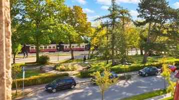 Eine Wohnstraße mit parkenden Autos, einem Fußweg und einem Zug im Hintergrund.