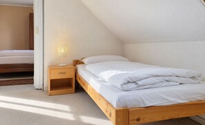 Ein Einzelbett mit Holzrahmen und einem Nachttisch mit Lampe.