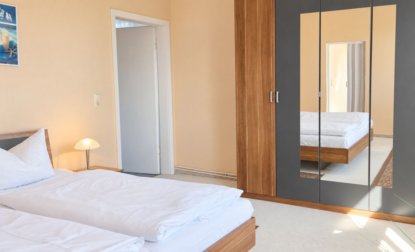 Ein Schlafzimmer mit Bett, Nachttisch, Lampe, Schrank und Spiegel.