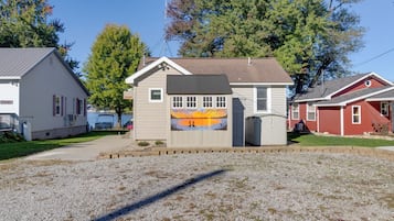A small, single-story building with a flat roof, a small porch, and a mural on the side.