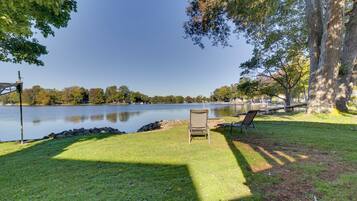 Vista de un lago con un área verde, una silla y un banco.