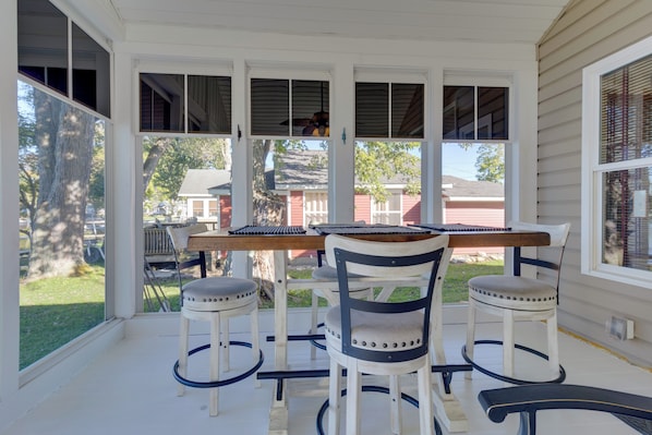 A covered porch with a wooden table and four chairs.