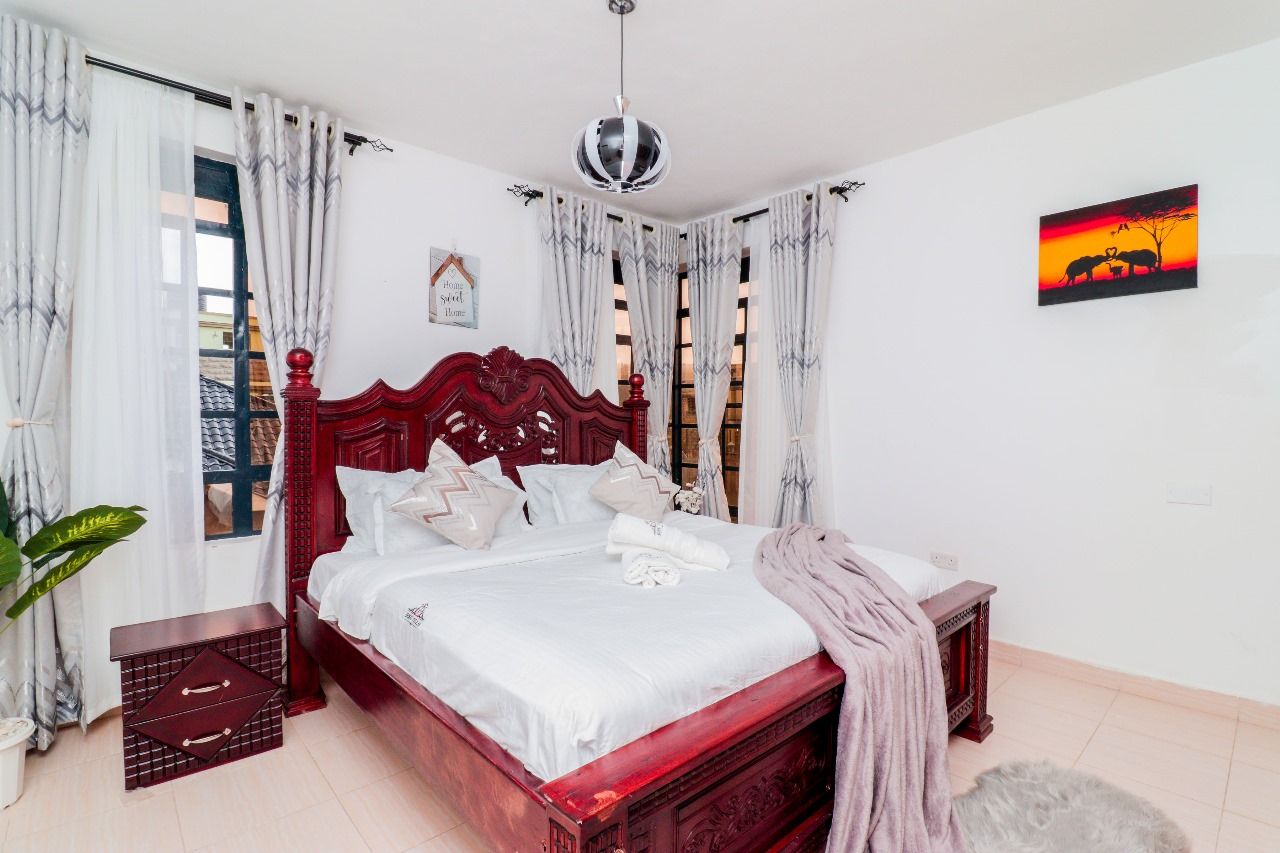 A bedroom with a wooden bed, white bedding, a hanging light fixture, and a wall-mounted picture.