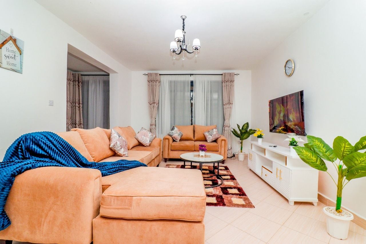A living room with a sofa, a coffee table, a TV, and a chandelier.