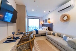 A modern hotel room with a bed, sofa, dining area, and a TV mounted on the wall. - Luxury & Fun in Santa Marta, 50 meters from the ocean (Santa Marta)