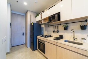 A modern kitchen with a built-in microwave, stove, and oven, along with a sink and hanging utensils. - Luxury & Fun in Santa Marta, 50 meters from the ocean (Santa Marta)
