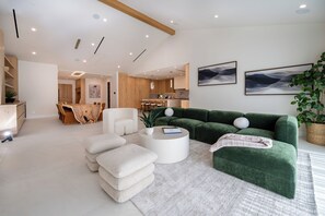 Ein modernes Wohnzimmer mit einem grünen Sofa, weißen Sesseln und einem runden Couchtisch.