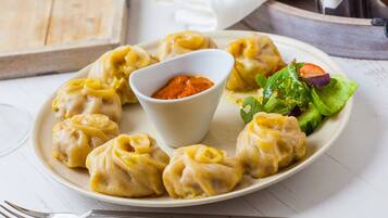 A plate of dumplings with a side of salad and a dipping sauce.