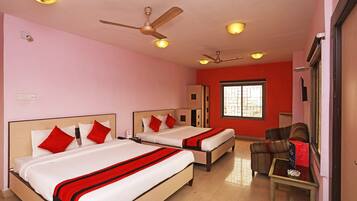 A hotel room with two beds, a ceiling fan, and a window with bars.
