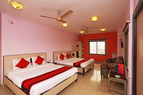 A hotel room with two beds, a ceiling fan, and a window with bars.