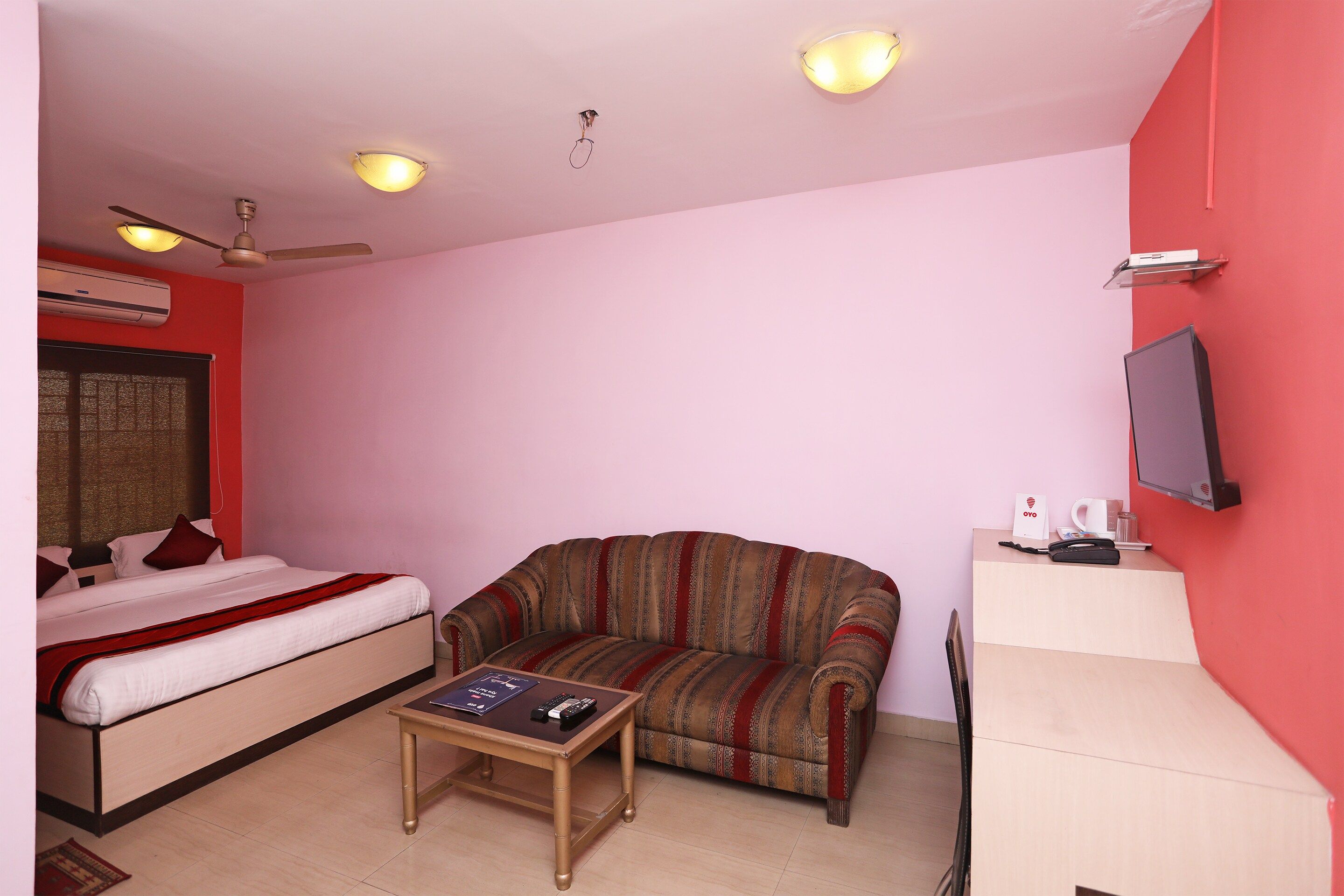Una habitación con cama, sofá, mesa de centro, televisor y aire acondicionado.