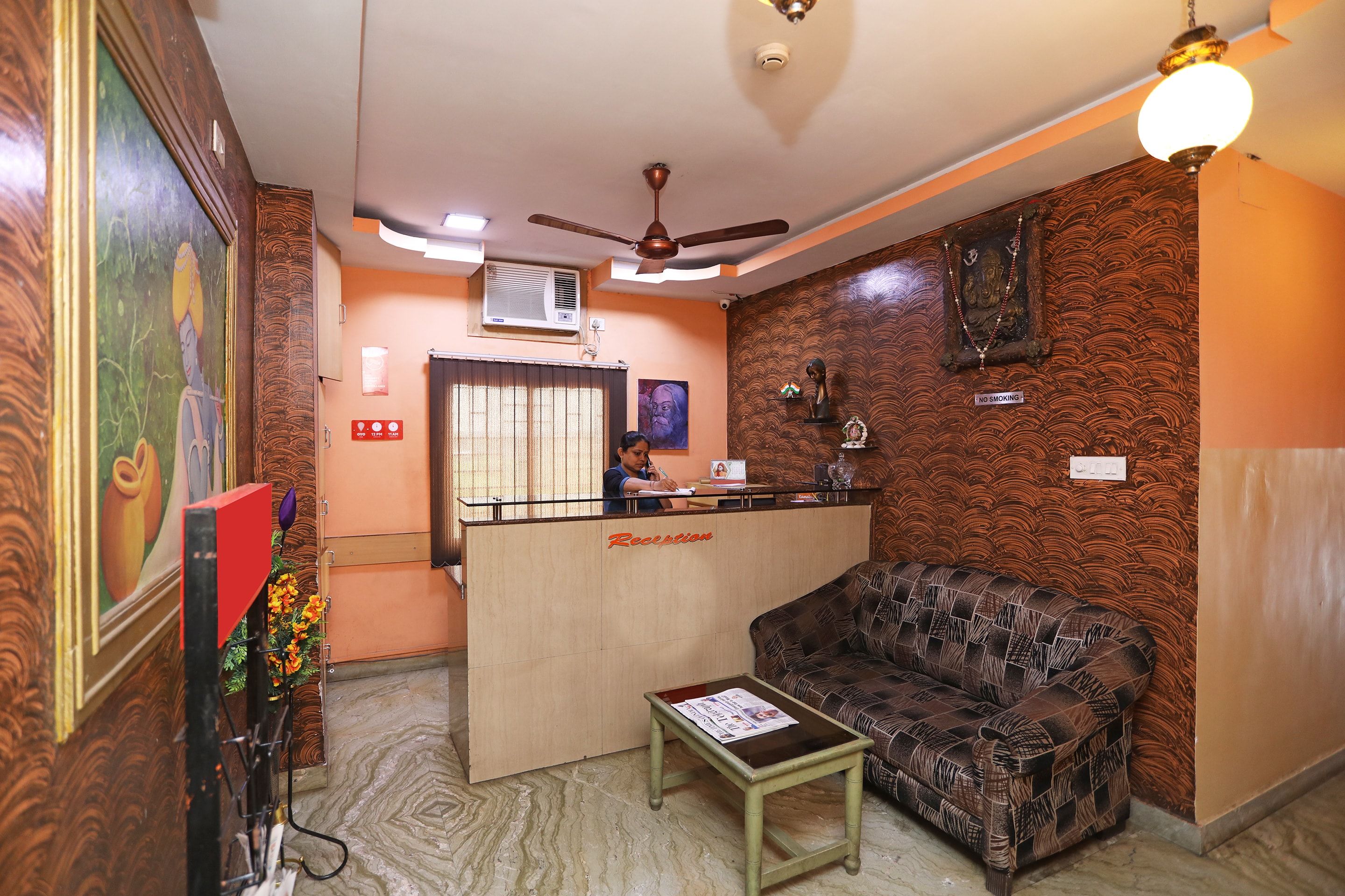 A reception area with a reception desk, a sofa, a small table, and a ceiling fan.