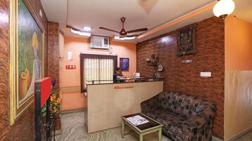 A reception area with a reception desk, a sofa, a small table, and a ceiling fan.