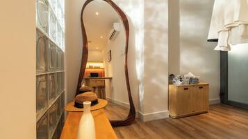 A room with a wooden floor, a large mirror, a woven basket, and a wooden cabinet with laundry baskets.