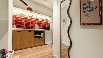 A modern kitchen with wooden cabinets, a red backsplash, and a microwave.