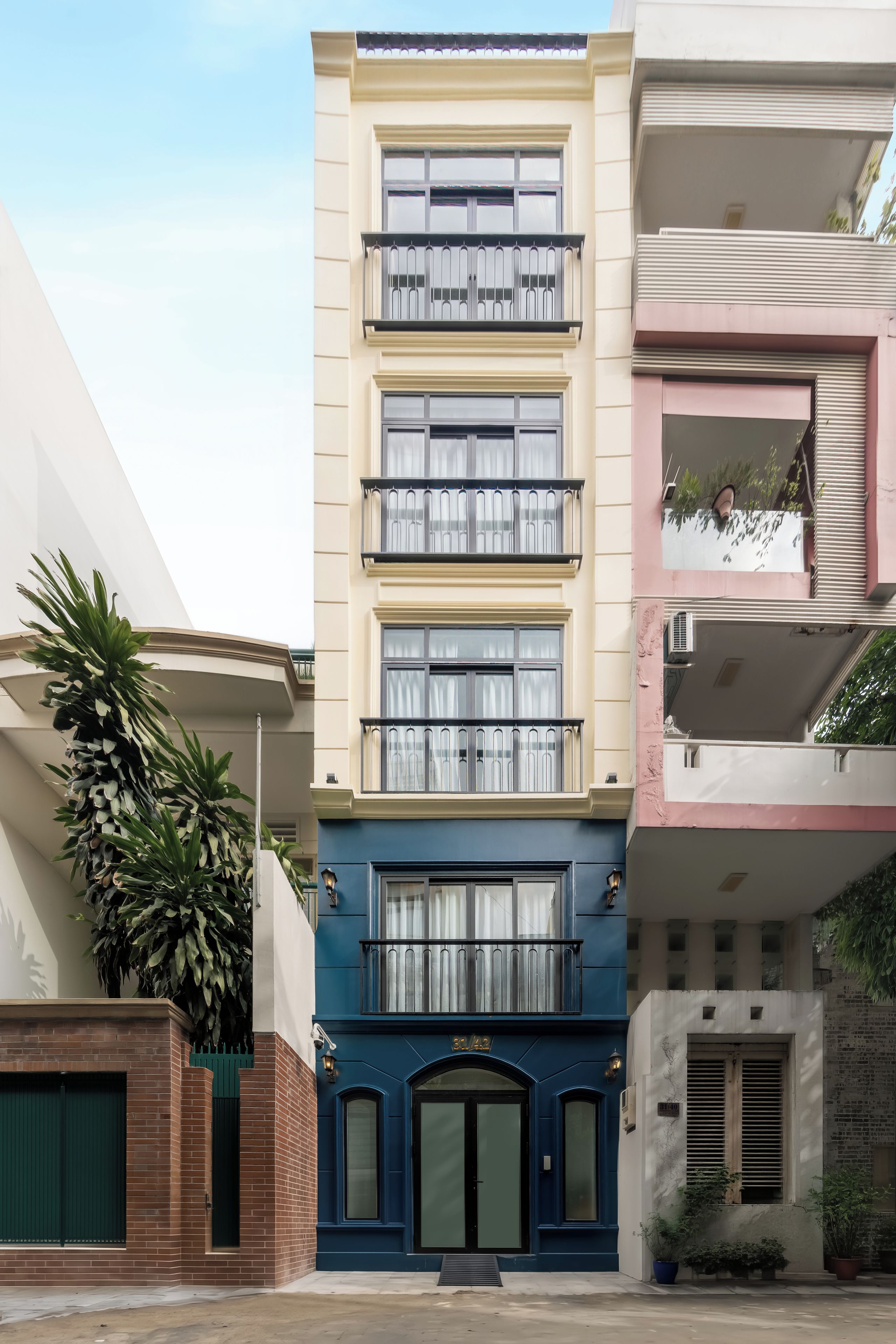 Een meerlaags woongebouw met een blauwe gevel, een balkon op de tweede verdieping en een zichtbaar huisnummer.