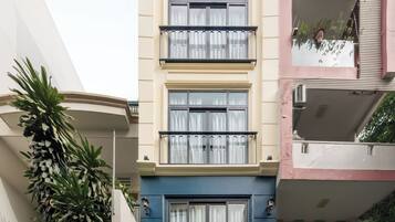 Een meerlaags woongebouw met een blauwe gevel, een balkon op de tweede verdieping en een zichtbaar huisnummer.