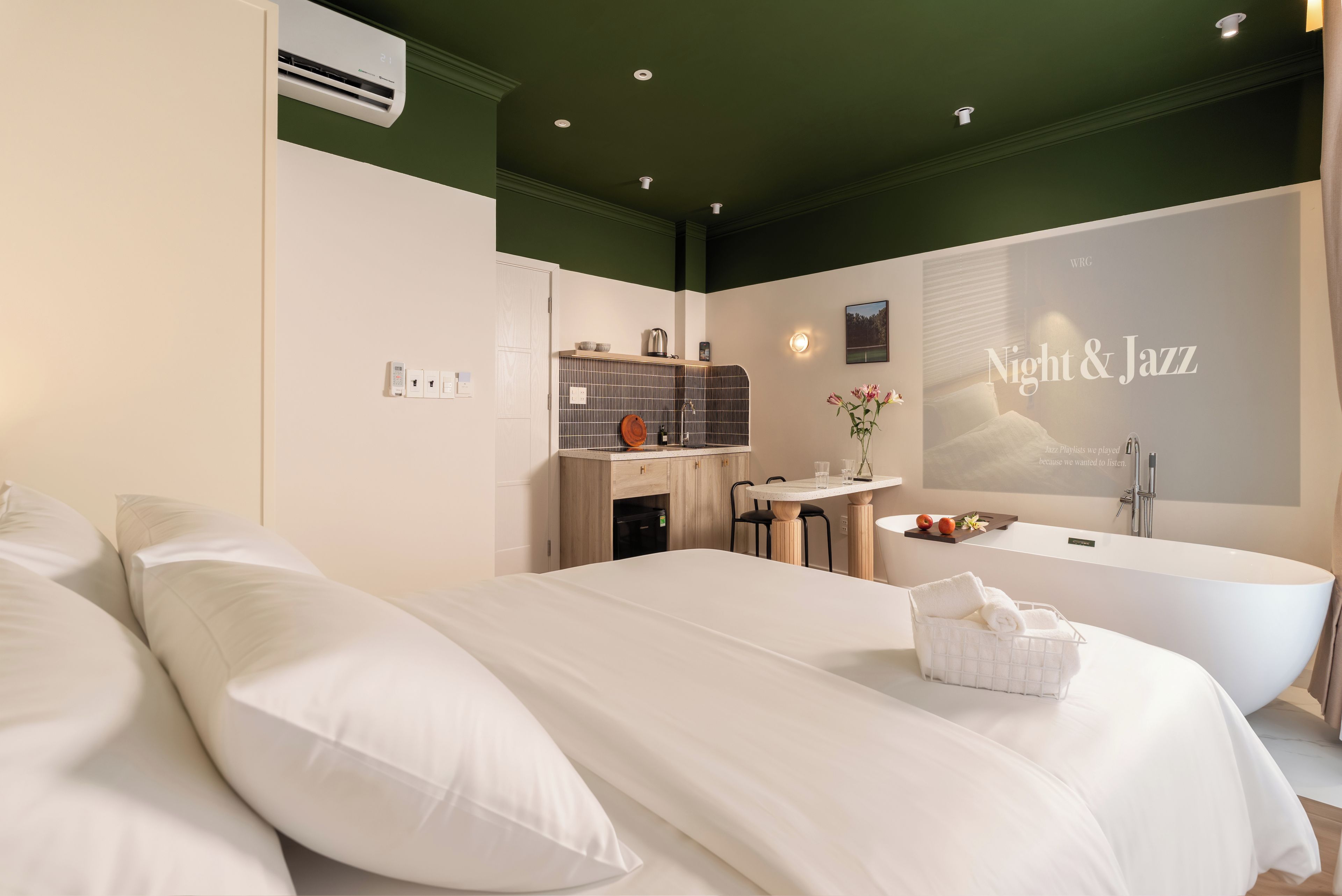 Een hotelkamer met een groot bed, een badkuip, een kitchenette en een luchtverkoeler aan de muur.