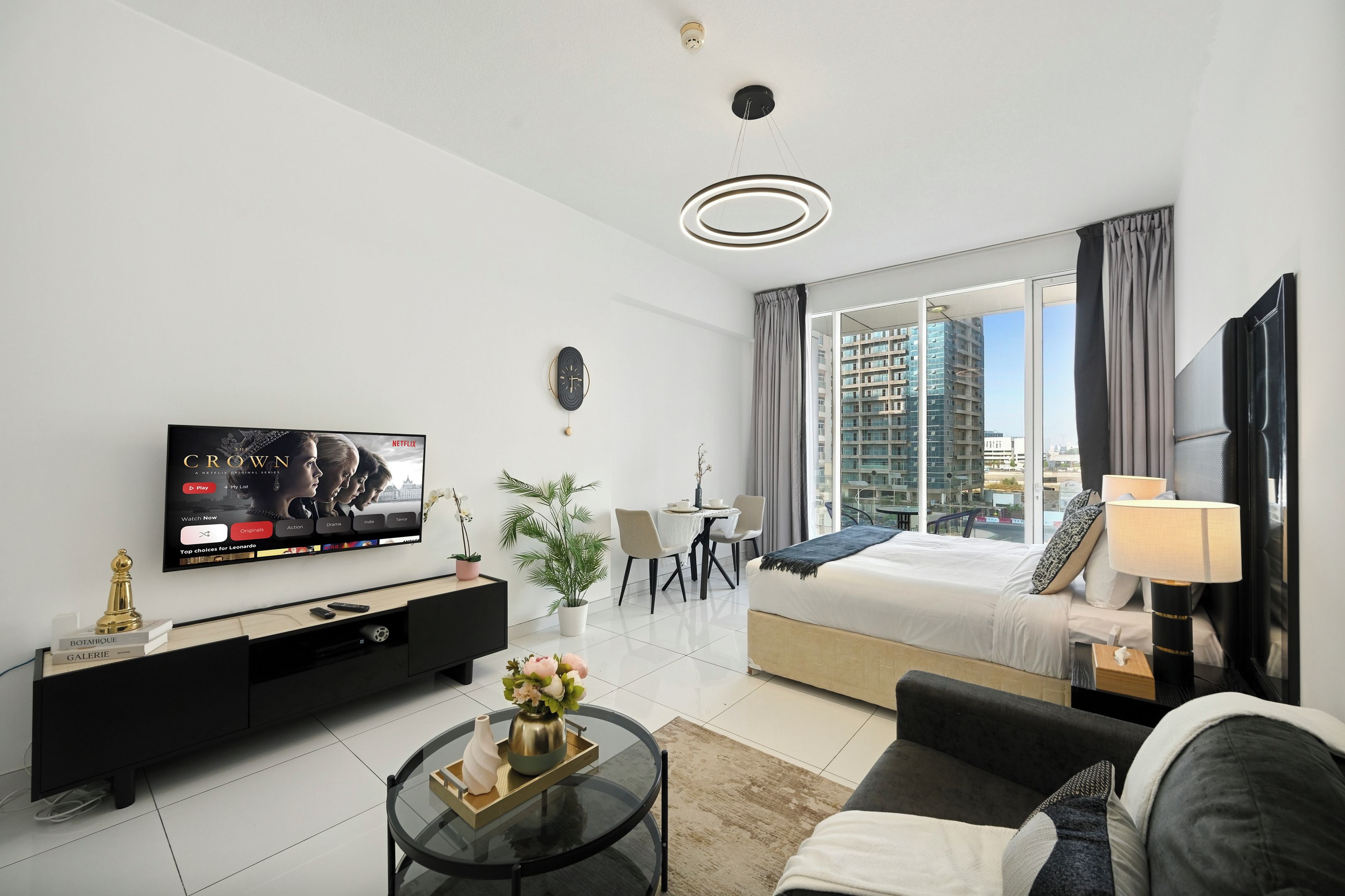 Ein modernes Hotelzimmer mit großem Flachbildfernseher, einer Couch, einem Essbereich und einem Bett mit Blick auf die Stadt.