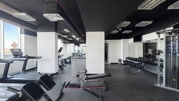 Une salle de sport équipée de tapis de course, d’appareils de musculation et de poids libres.