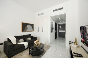 Ein modernes Wohnzimmer mit einem schwarzen Sofa, einem Glastisch und einem Bild an der Wand.