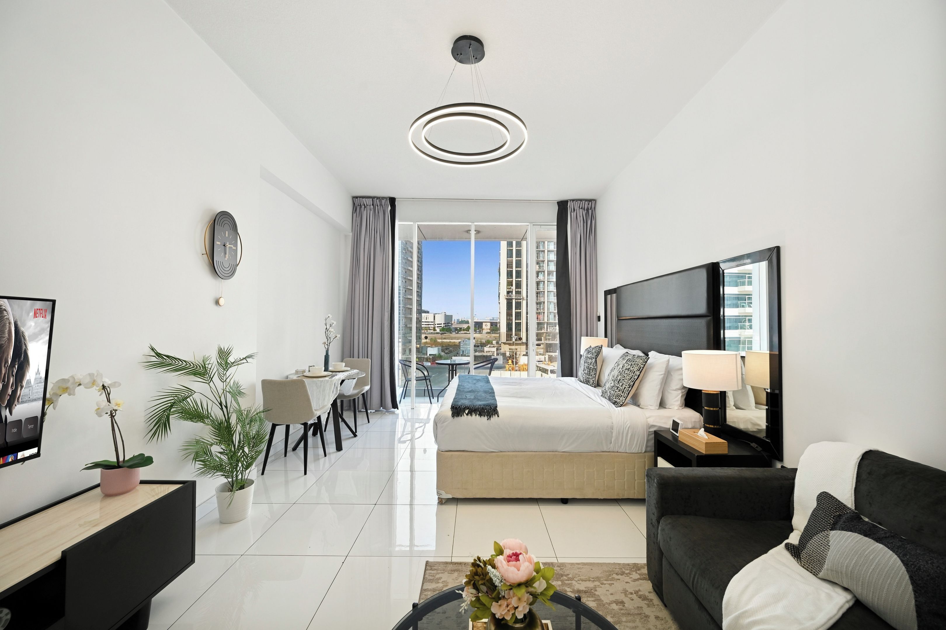 A modern hotel room with a bed, a desk, a chair, a coffee table, and a TV.