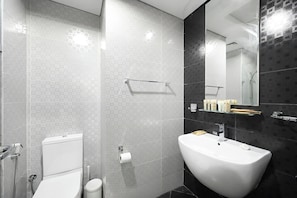 Een moderne badkamer met een wit wastafelmeubel, toilet en douche.