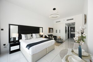 Een moderne hotelkamer met een groot bed, nachtkastjes, een bureau en een zichtbare badkamer door een geopende deur.
