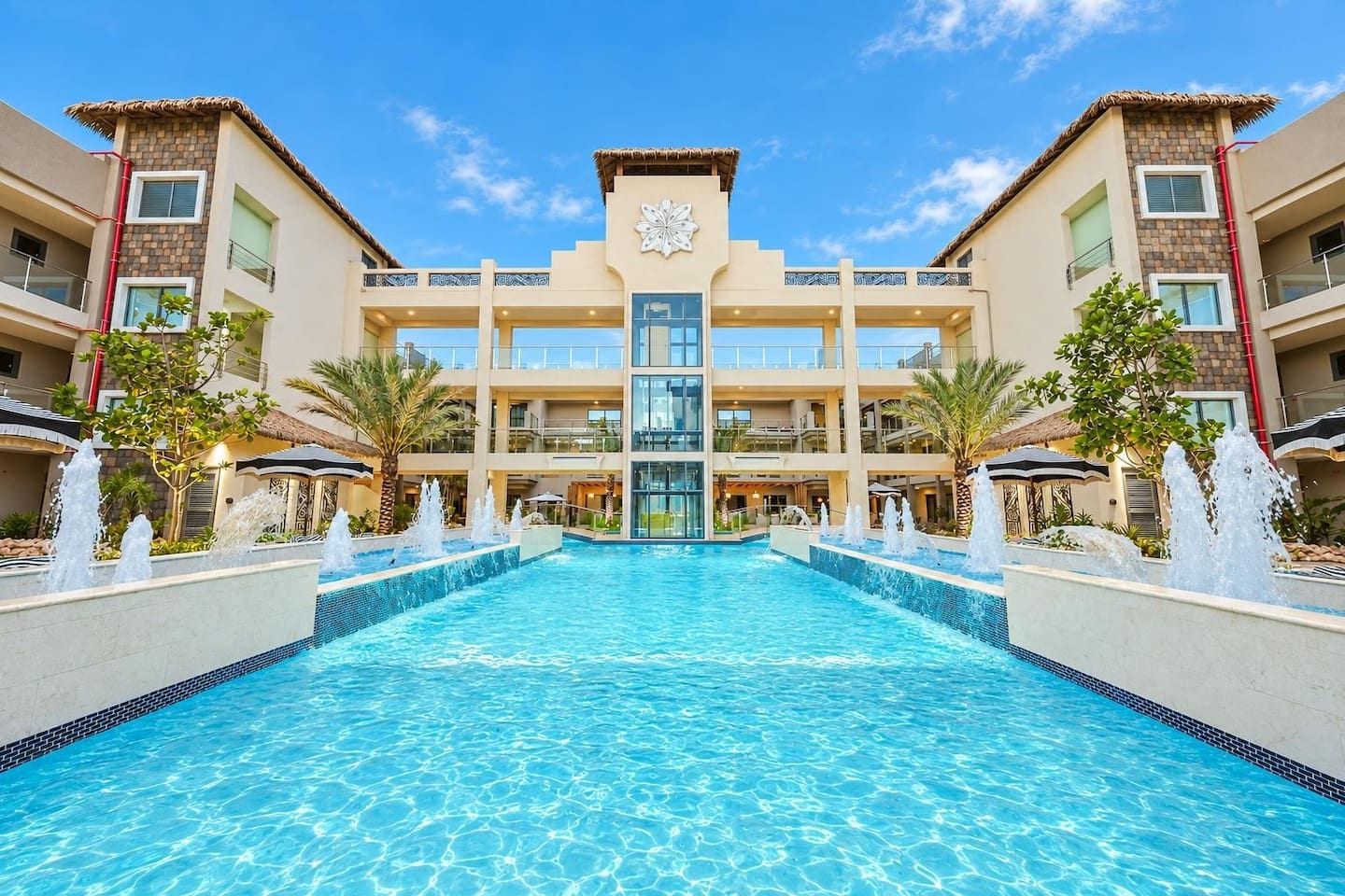 Un hôtel doté d’une piscine centrale, de nombreux balcons et d’une façade décorative.