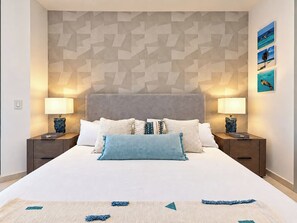 Ein Schlafzimmer mit einem großen Bett, zwei Nachttischen und einer Wand mit geometrischem Muster.
