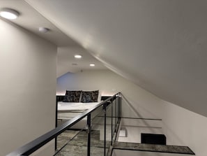 A modern staircase with a metal railing leading to a bedroom with a bed and a nightstand. - Charming 2-Bedroom Apartment in Heart of Prague (Prague)
