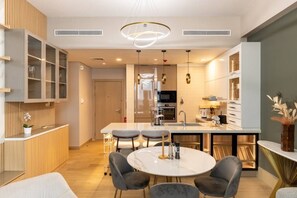 A modern kitchen with a central island, built-in appliances, and a dining area with a round table and chairs. - La Rive - Stylish 2 Bedroom Apartment (Dubai)