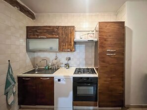 Una cocina compacta con muebles de madera, un lavamanos de acero inoxidable, lavavajillas y horno empotrado.