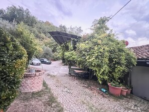 Ein gepflasterter Weg führt zu einem Haus mit einer Ziegelmauer und einem kleinen Garten.