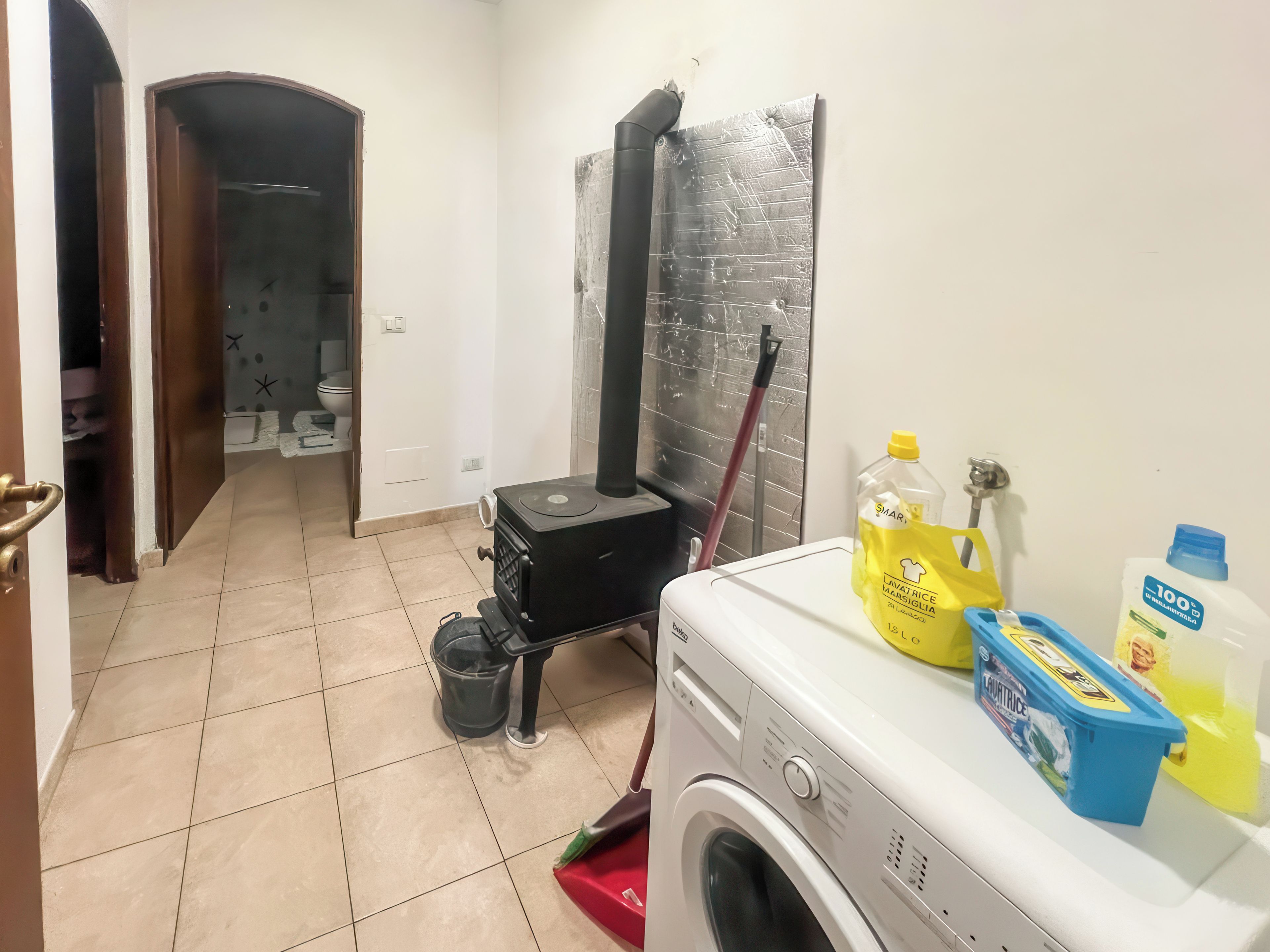 A laundry area with a washing machine, a mop, and cleaning supplies.