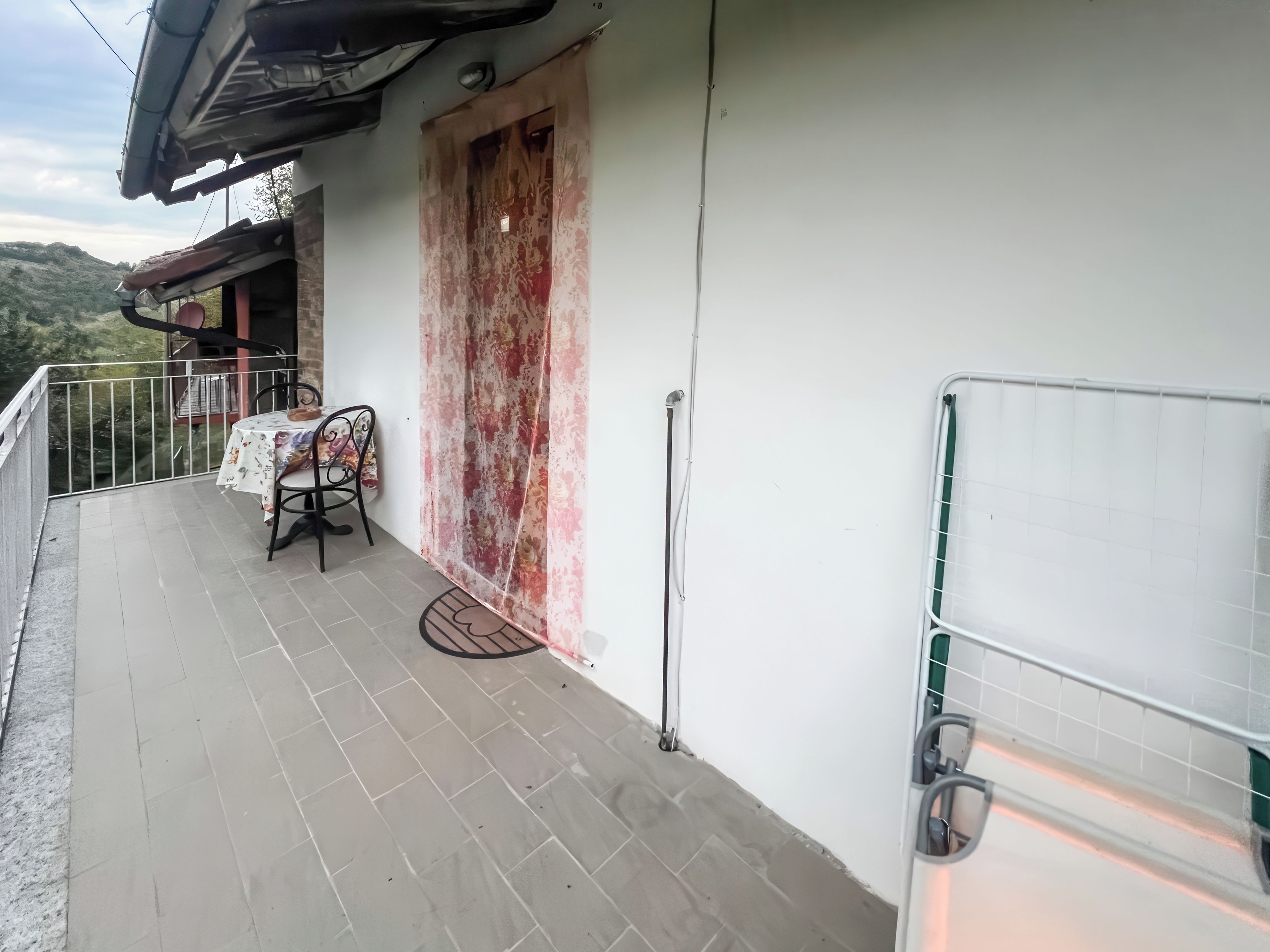 A balcony with a table and chairs, a door, and a view of the mountains.