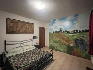 Un dormitorio con cama, un cuadro, una puerta y un mural en la pared.