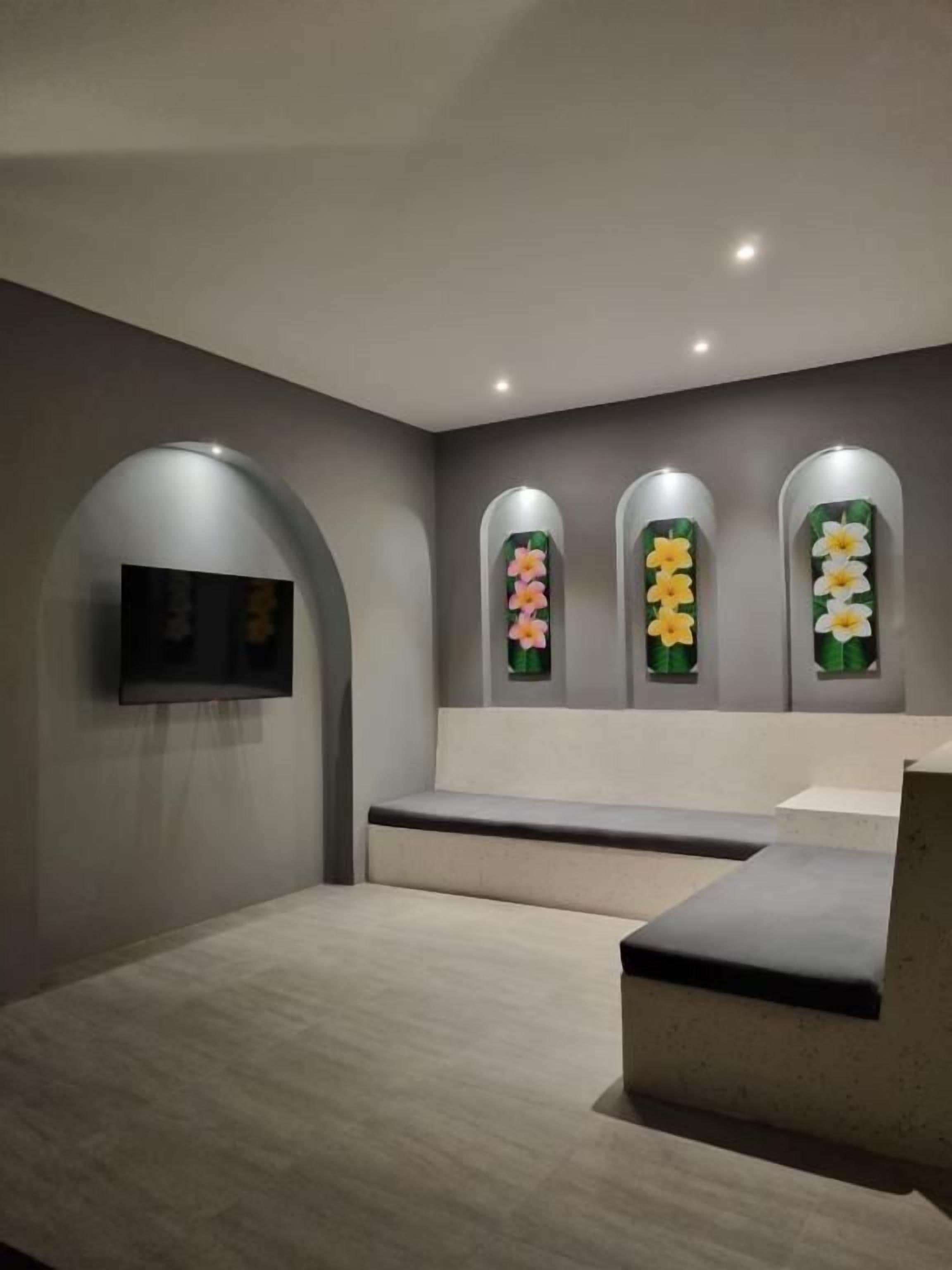 Una habitación con una cama, un televisor de pantalla plana en la pared y tres arreglos florales colgantes.