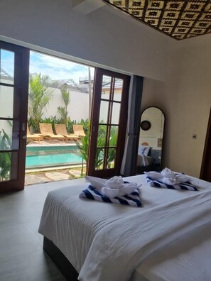 Quarto de hotel com cama, uma janela grande e vista para uma piscina.