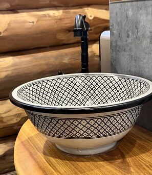 Eine weiße Keramikschale mit einem schwarzen geometrischen Muster auf einer Holzoberfläche.