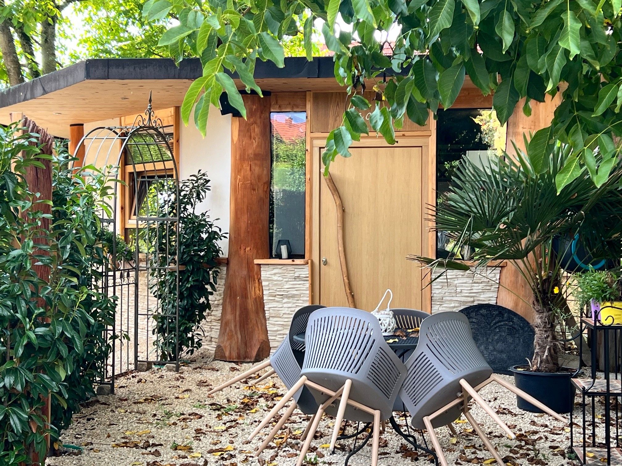 An outdoor seating area with two chairs and a table, surrounded by plants and a wooden fence.