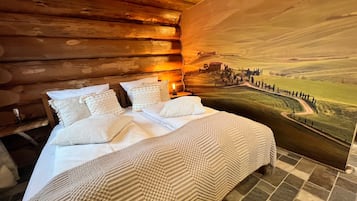 Une chambre à coucher avec un lit, des oreillers, une table de chevet et une grande fresque murale représentant un paysage.