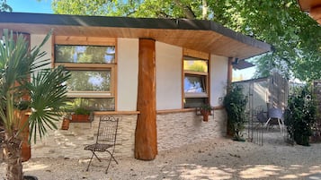 Ein modernes Haus mit Naturstein-Fassade, großen Fenstern und einer Schotterterrasse.