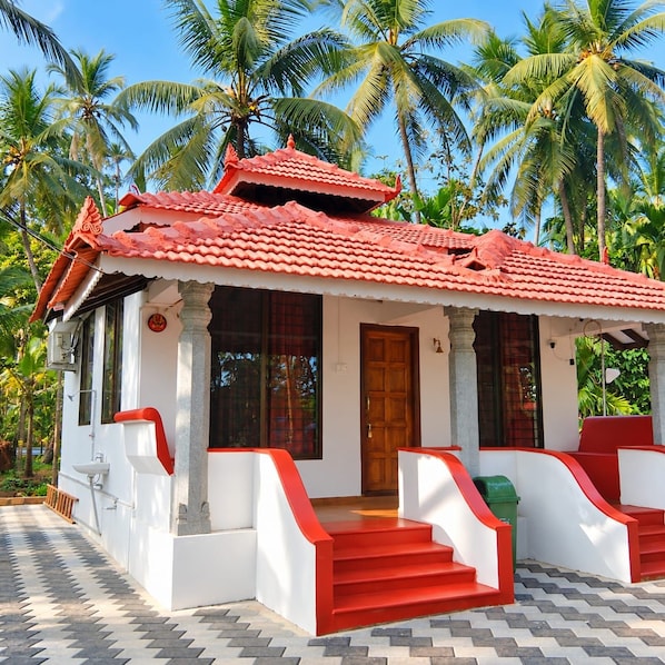A two-story building with a red-tiled roof, white walls, and a porch with red steps.