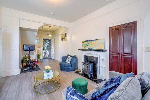 A living room with a fireplace, a blue sofa, a green ottoman, and a round coffee table.