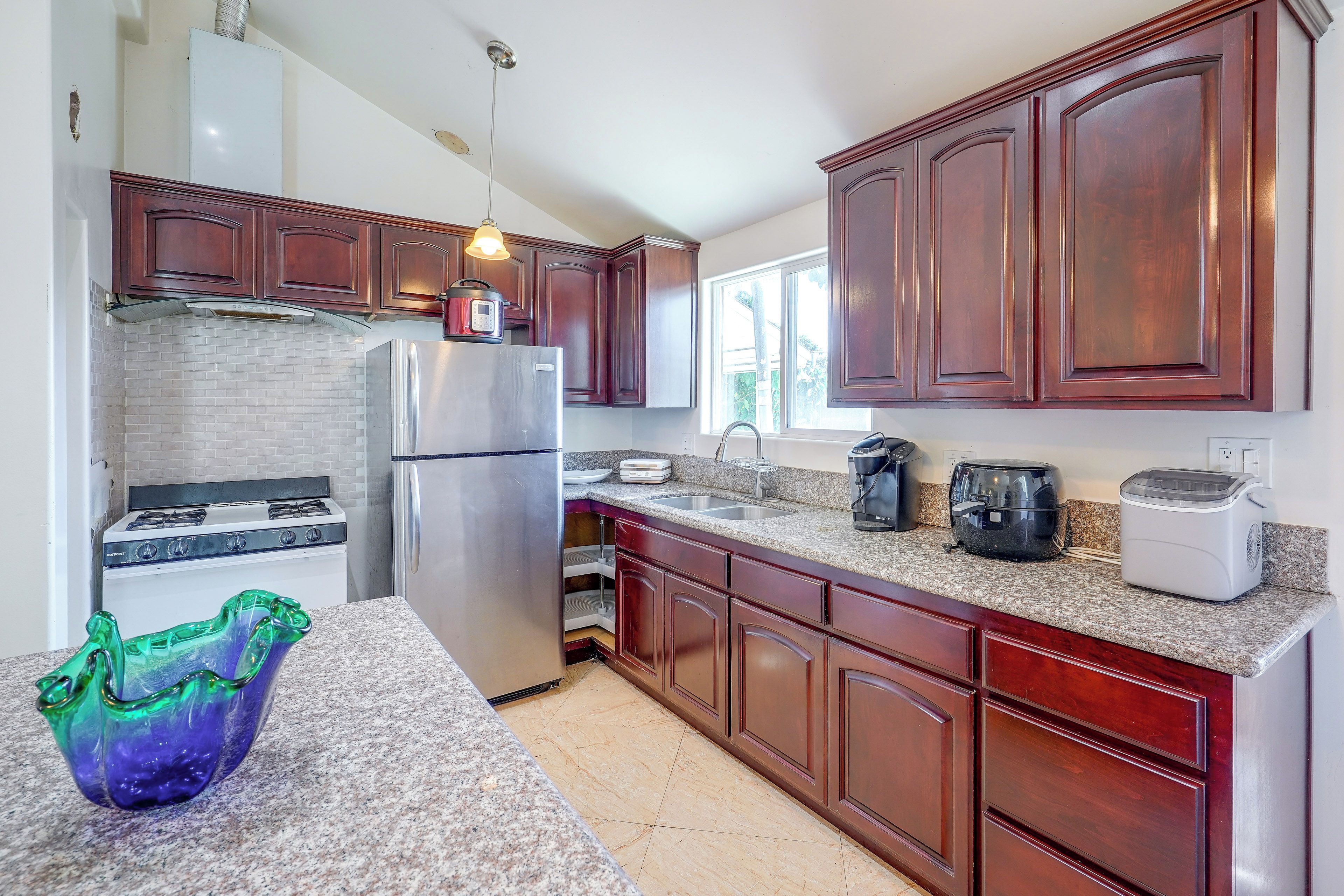 A modern kitchen with stainless steel appliances, wooden cabinets, and a granite countertop.