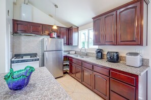 A modern kitchen with stainless steel appliances, wooden cabinets, and a granite countertop.