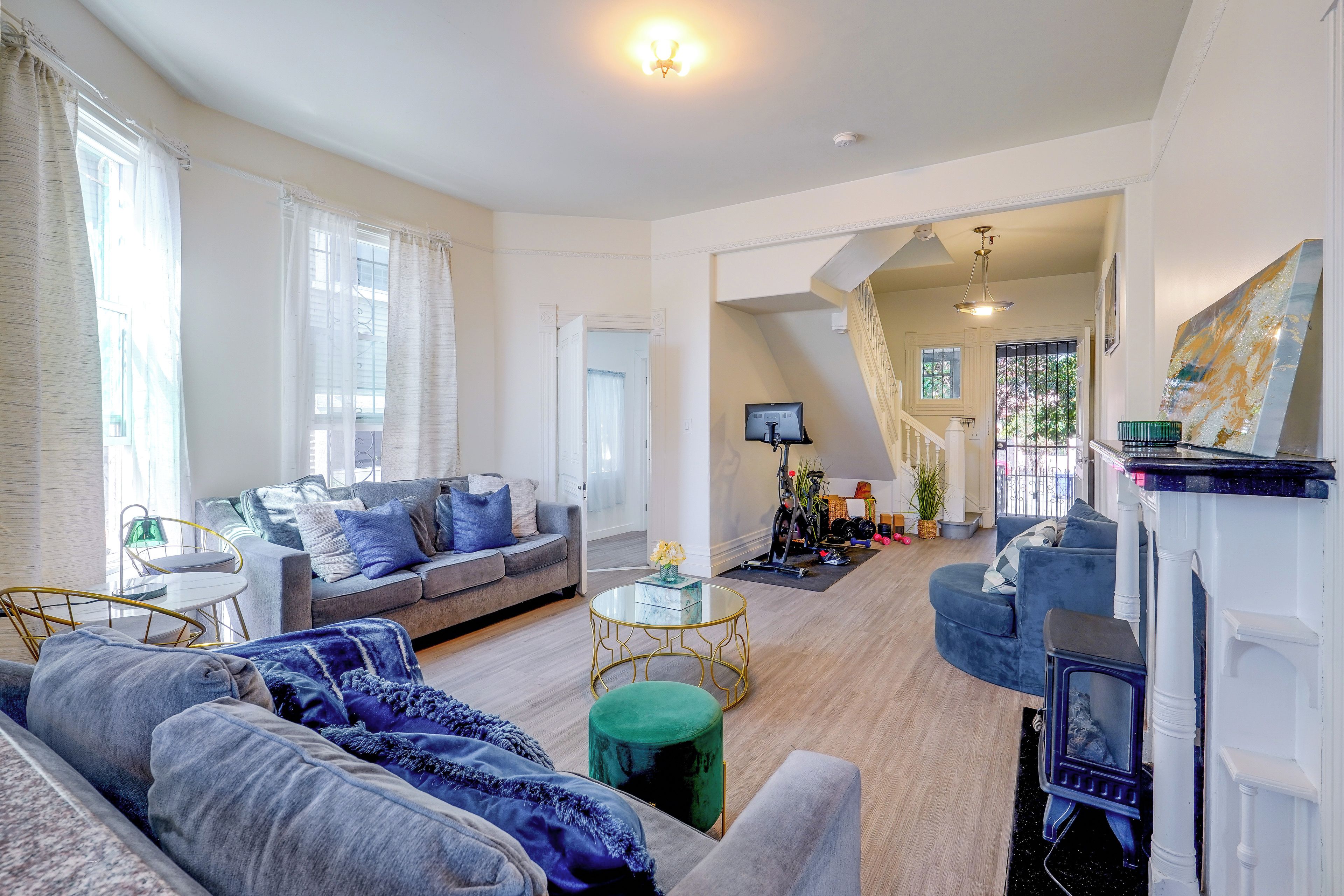 A spacious living room with a sofa, a coffee table, and a fireplace. There is a staircase leading to an upper level.